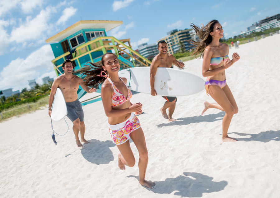 Florida Men and Women running with surfboards on the beach in Miami